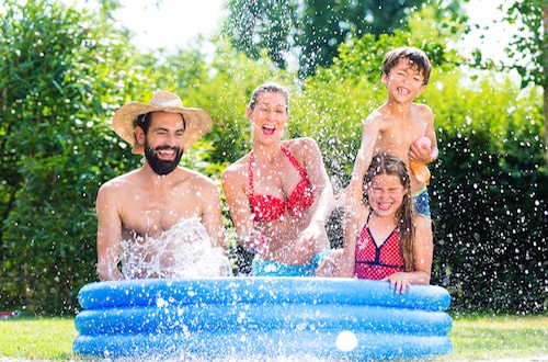 Familie im Planschbecken hat riesigen Spaß im Garten