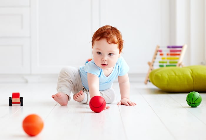 Baby krabbelt hinter Bällen her