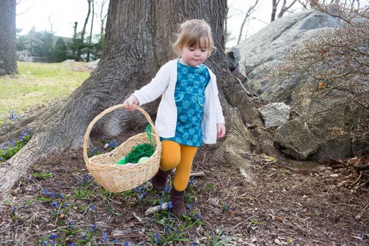 Ein kleines Mädchen mit einem Korb sammelt Ostergeschenke und Ostereier