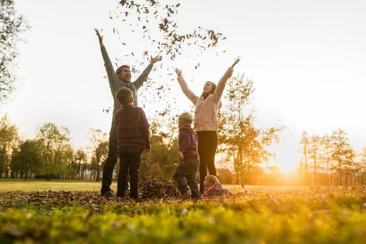 Familie wirft bunte Herbstblätter in die Luft